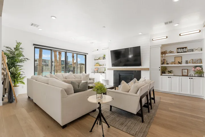 Spacious living area featuring wood-finish flooring, a fireplace with a dark surround, and built-in shelving with cabinetry