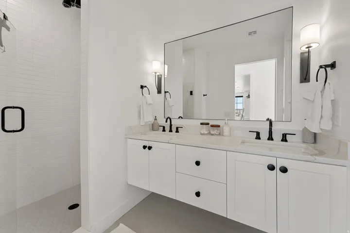 Spa-inspired primary bathroom featuring a floating vanity with dual sinks, quartz countertop, and matte black hardware