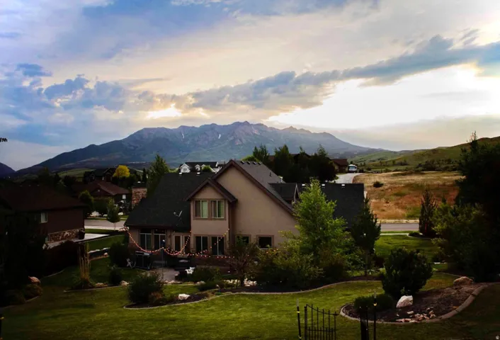 Expansive mountain backdrop with a landscaped backyard, multi-level home, and paved patio area