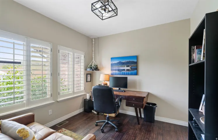 Wood-finish flooring, white window shutters, black open shelving, and a decorative ceiling light fixture