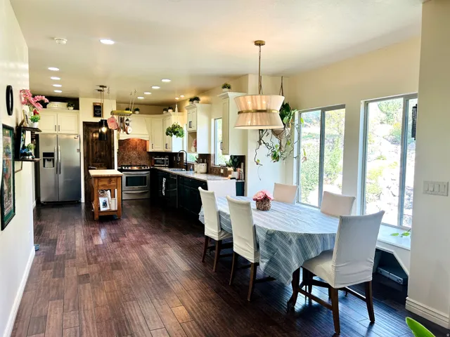 Open-concept kitchen and dining area featuring wood-finish flooring, recessed lighting, and a large window bench