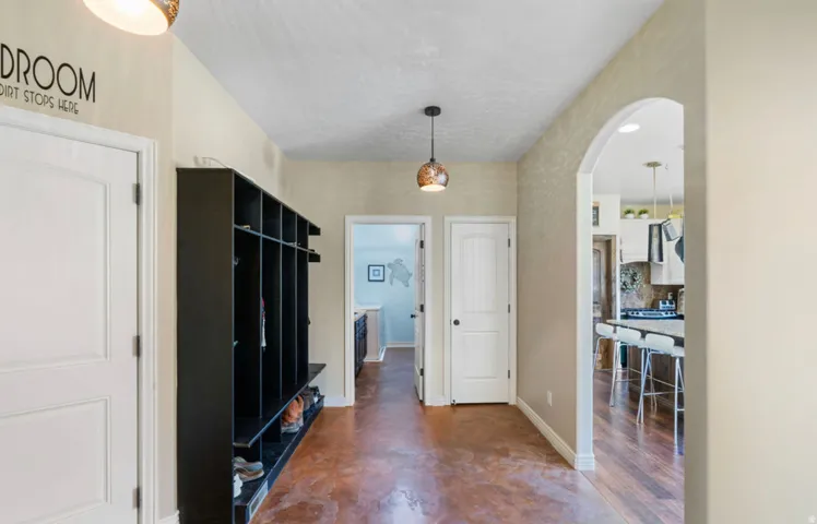 Hallway with a built-in storage unit, a pendant light fixture, an arched entryway, and a textured wall finish