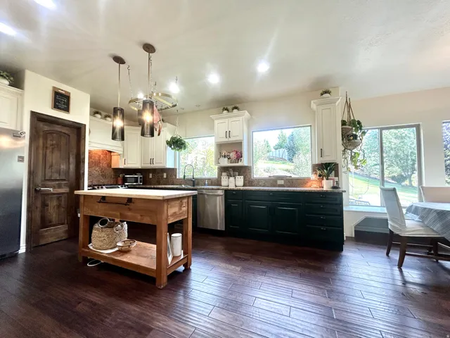 Kitchen featuring wood-finish flooring, two-tone cabinetry, stainless steel appliances, a wood kitchen island, and recessed lighting