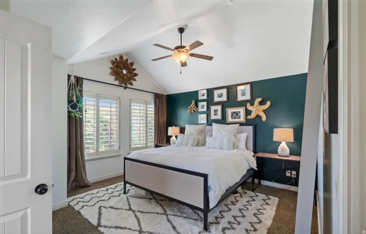 Vaulted ceiling with a ceiling fan, two windows with plantation shutters, accent wall, and carpet flooring