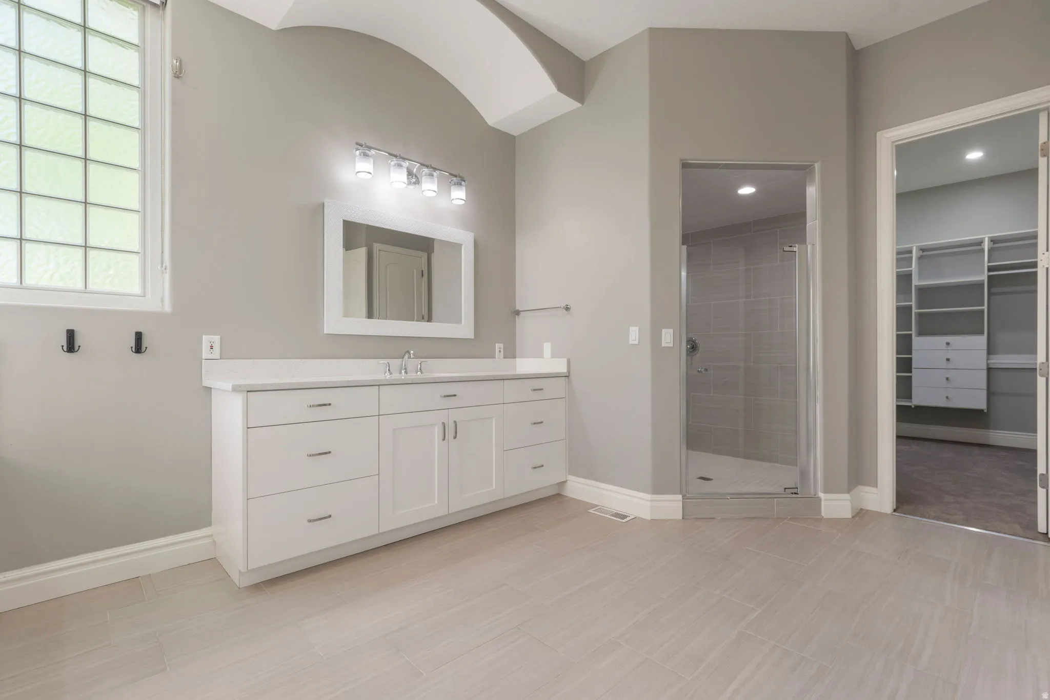 Elongated vanity with dual sinks, white cabinetry, and a light-colored countertop