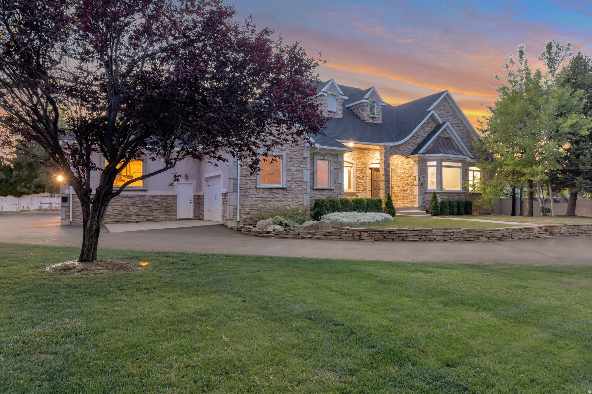 Stone and stucco exterior with a dark-pitched roof, dormer windows, and a covered entry