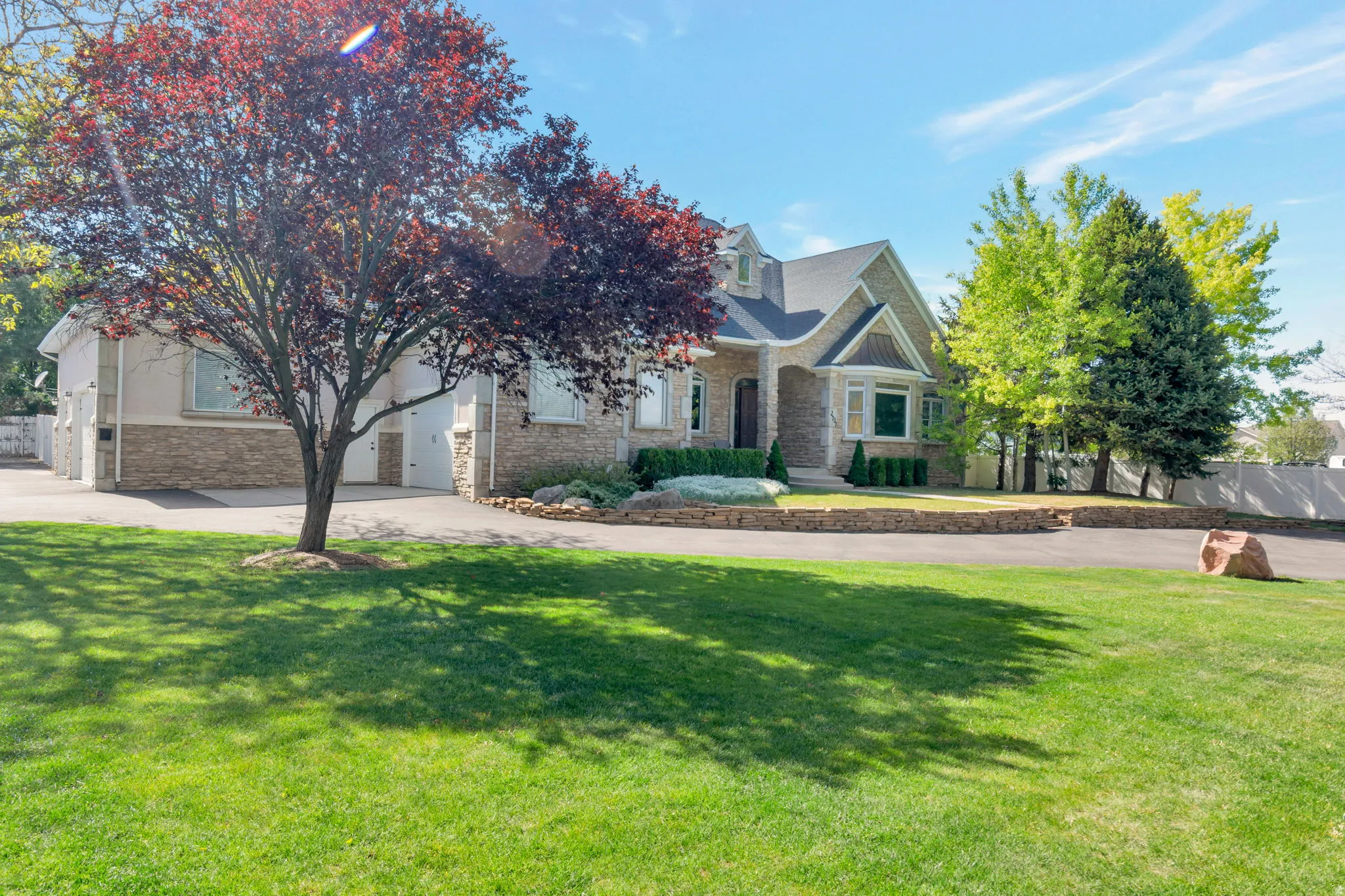 Stone and stucco exterior, arched portico entrance, multi-pane bay window, attached two-car garage, and a paved driveway