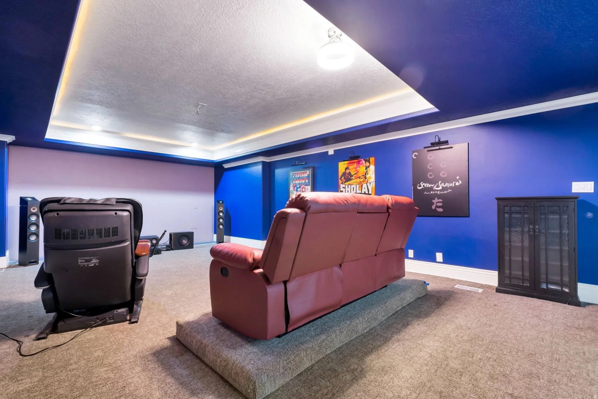 Recessed ceiling with perimeter lighting, wall-mounted light fixtures, built-in wall speakers, and carpet flooring
