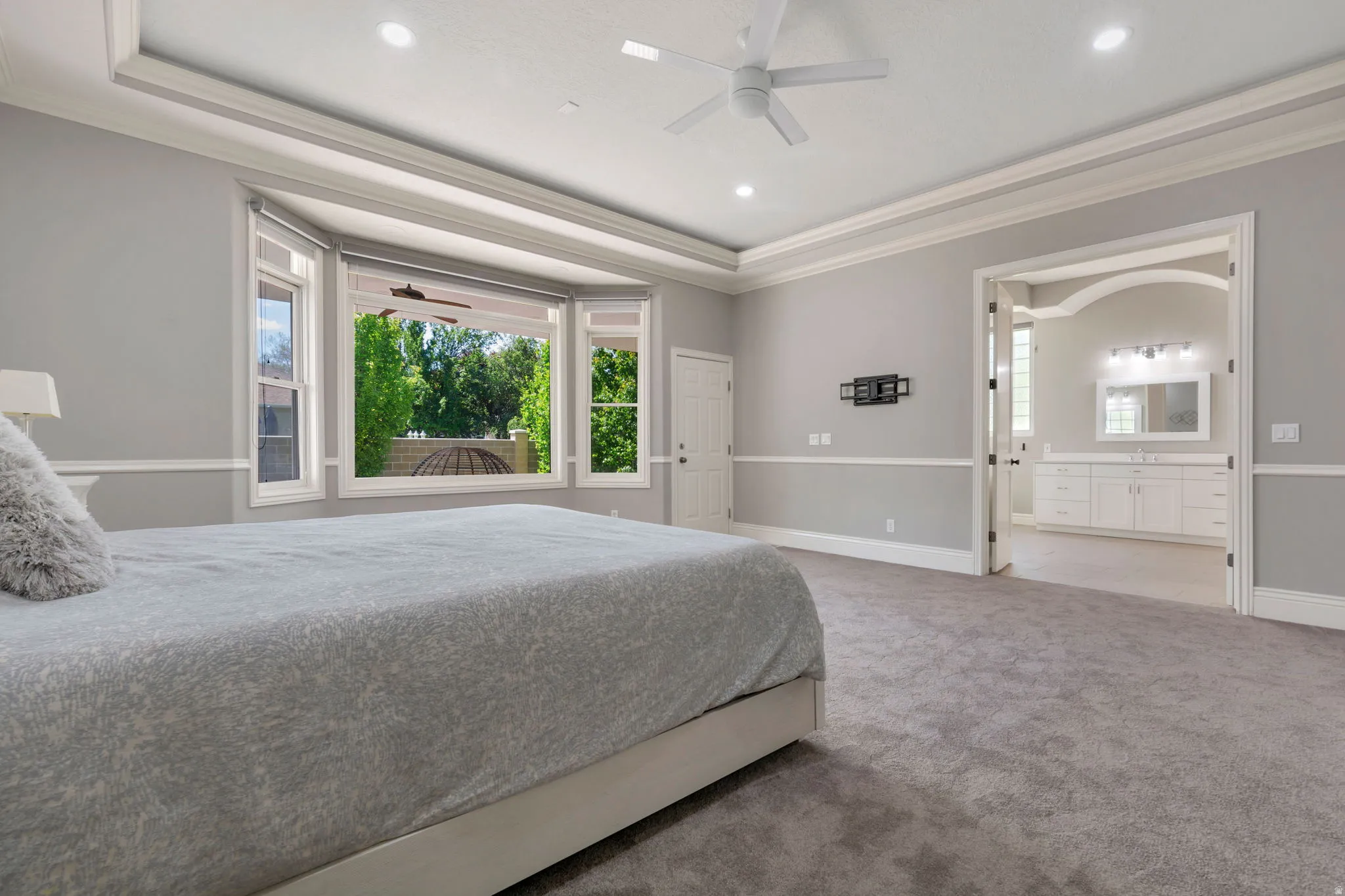 Recessed lighting, ceiling fan, crown molding, bay window, and a dual vanity with built-in cabinetry