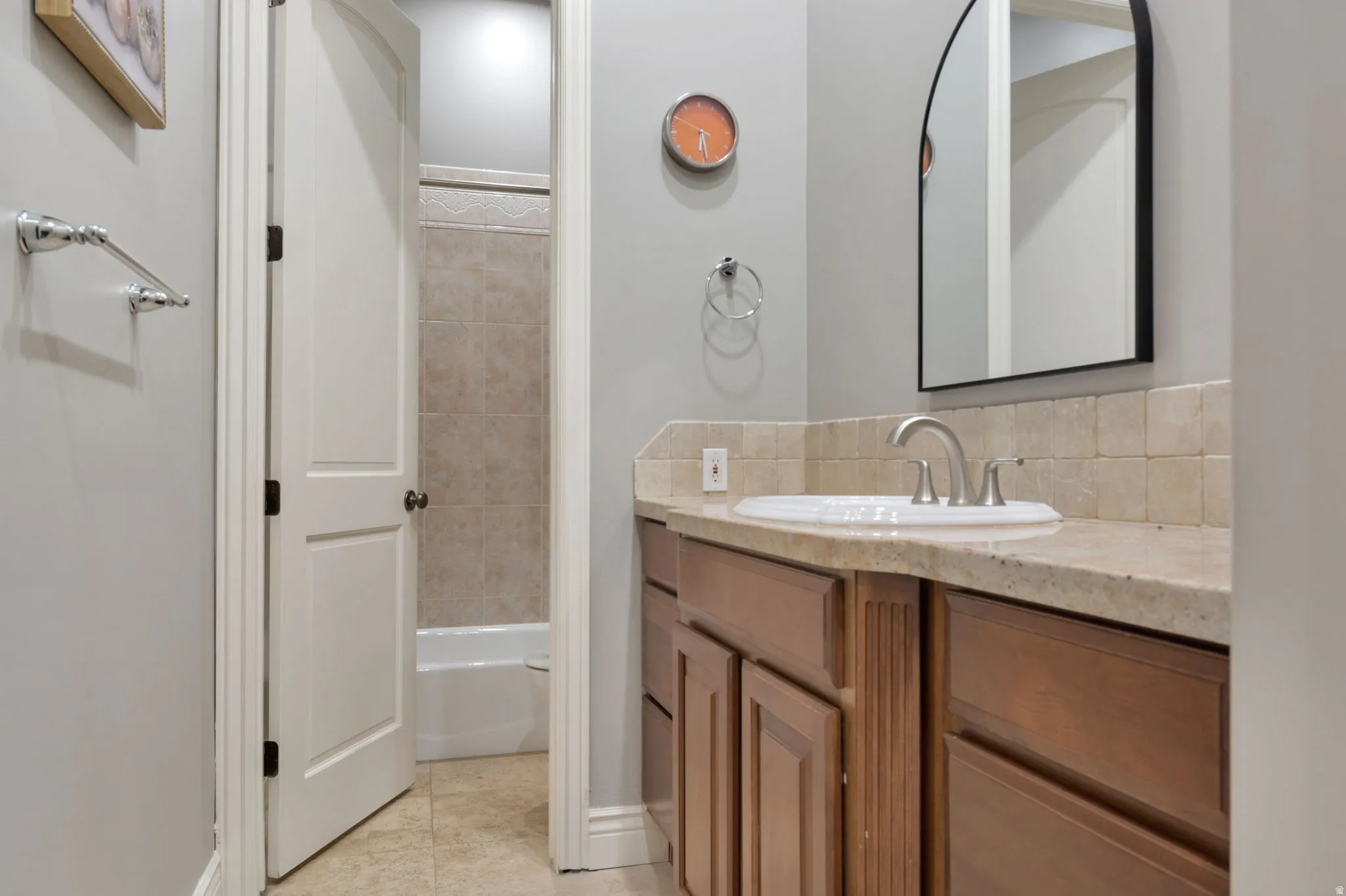 Bathroom featuring a wood-finish vanity with an integrated sink, stone countertop, and tile backsplash