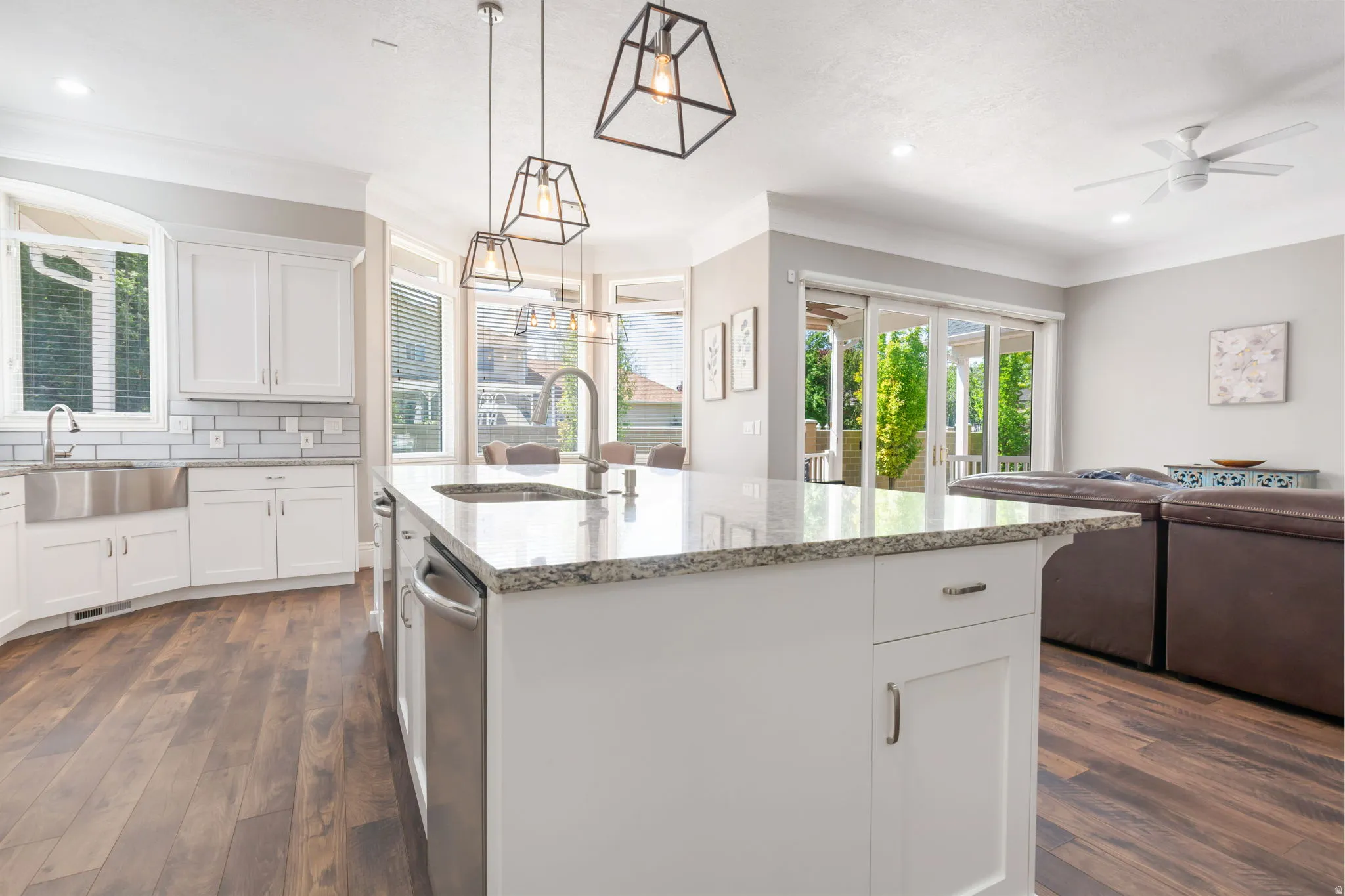 White cabinetry with stainless steel hardware, granite countertops, wood-finish flooring, recessed lighting, and sliding glass doors