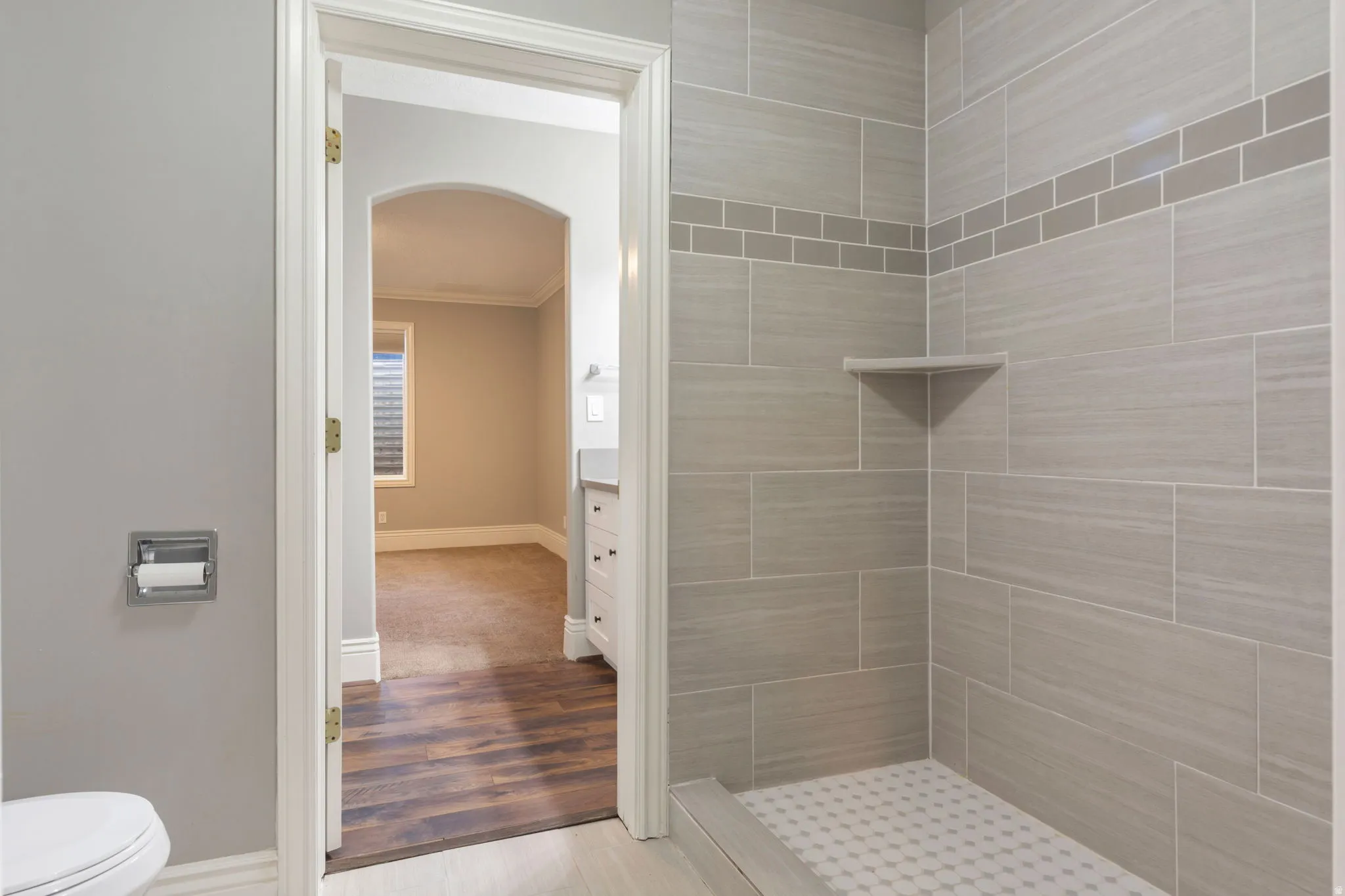 Tiled shower with a decorative accent band and built-in corner shelf