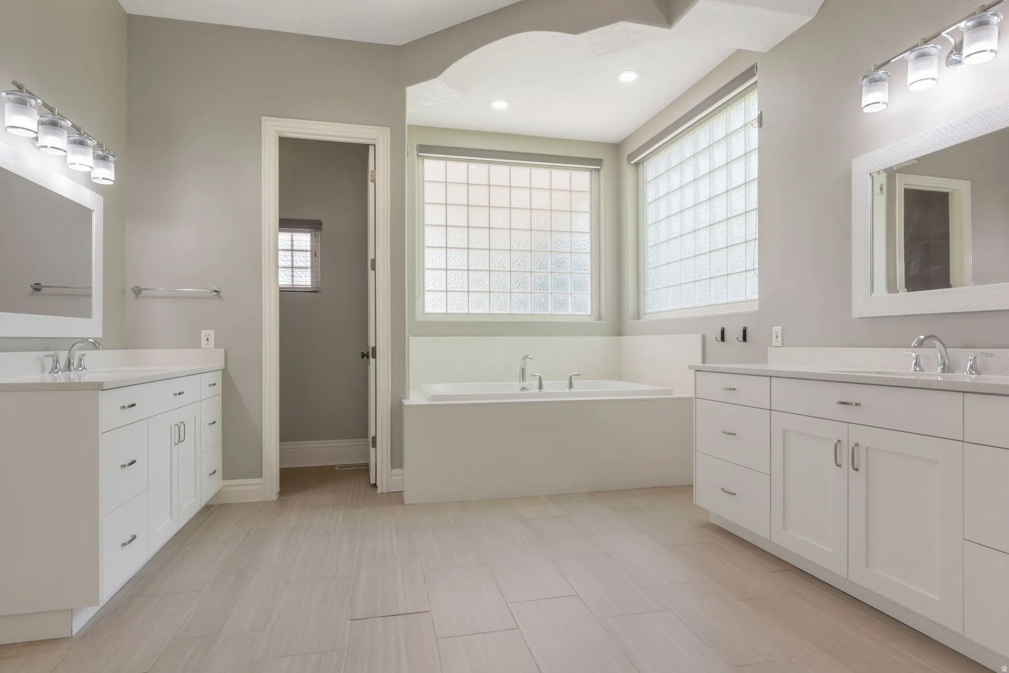 Dual vanities with white cabinetry, undermount sinks, and polished chrome fixtures