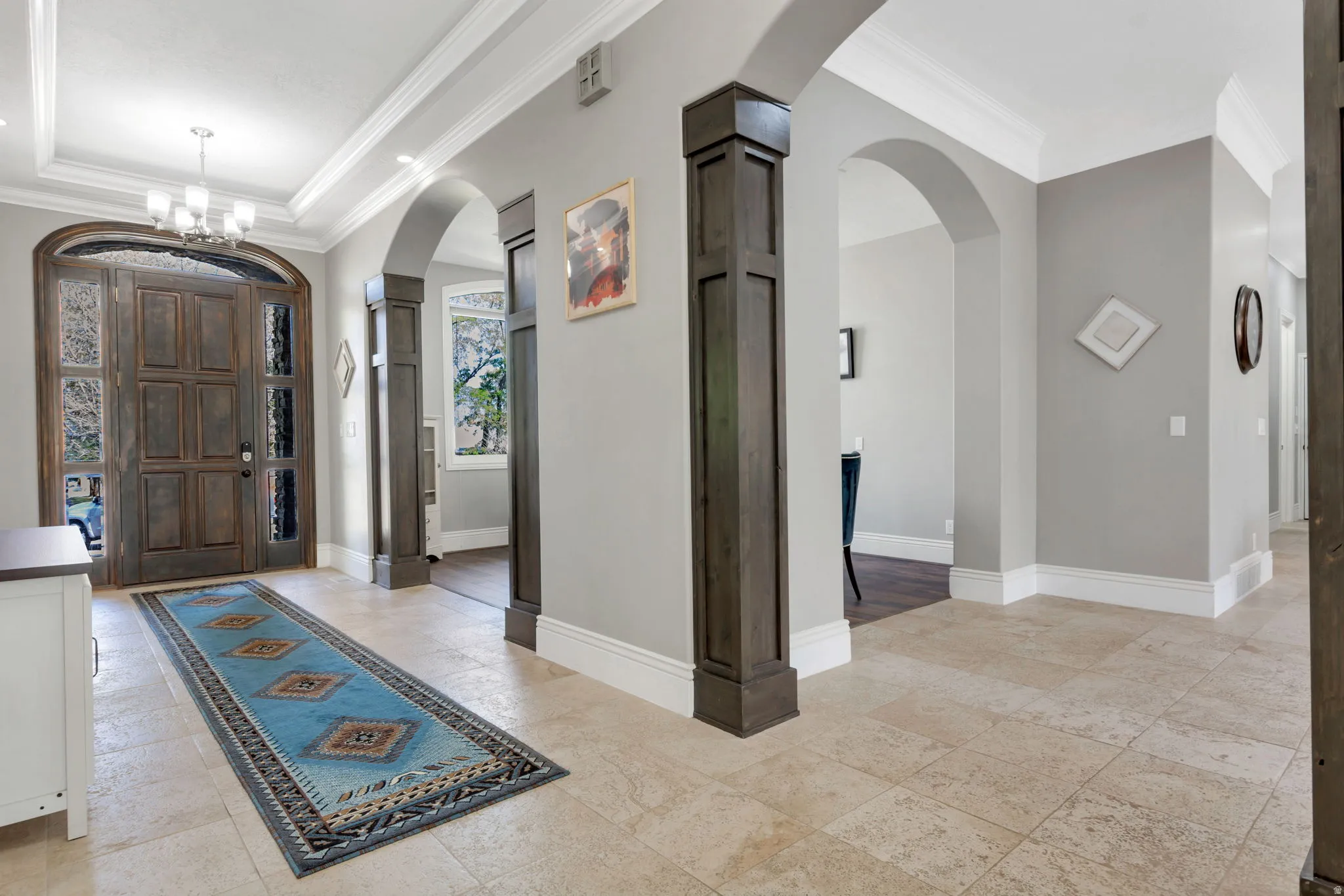 Grand entryway featuring a wood-panel door with sidelights, a tray ceiling with crown molding, and recessed lighting