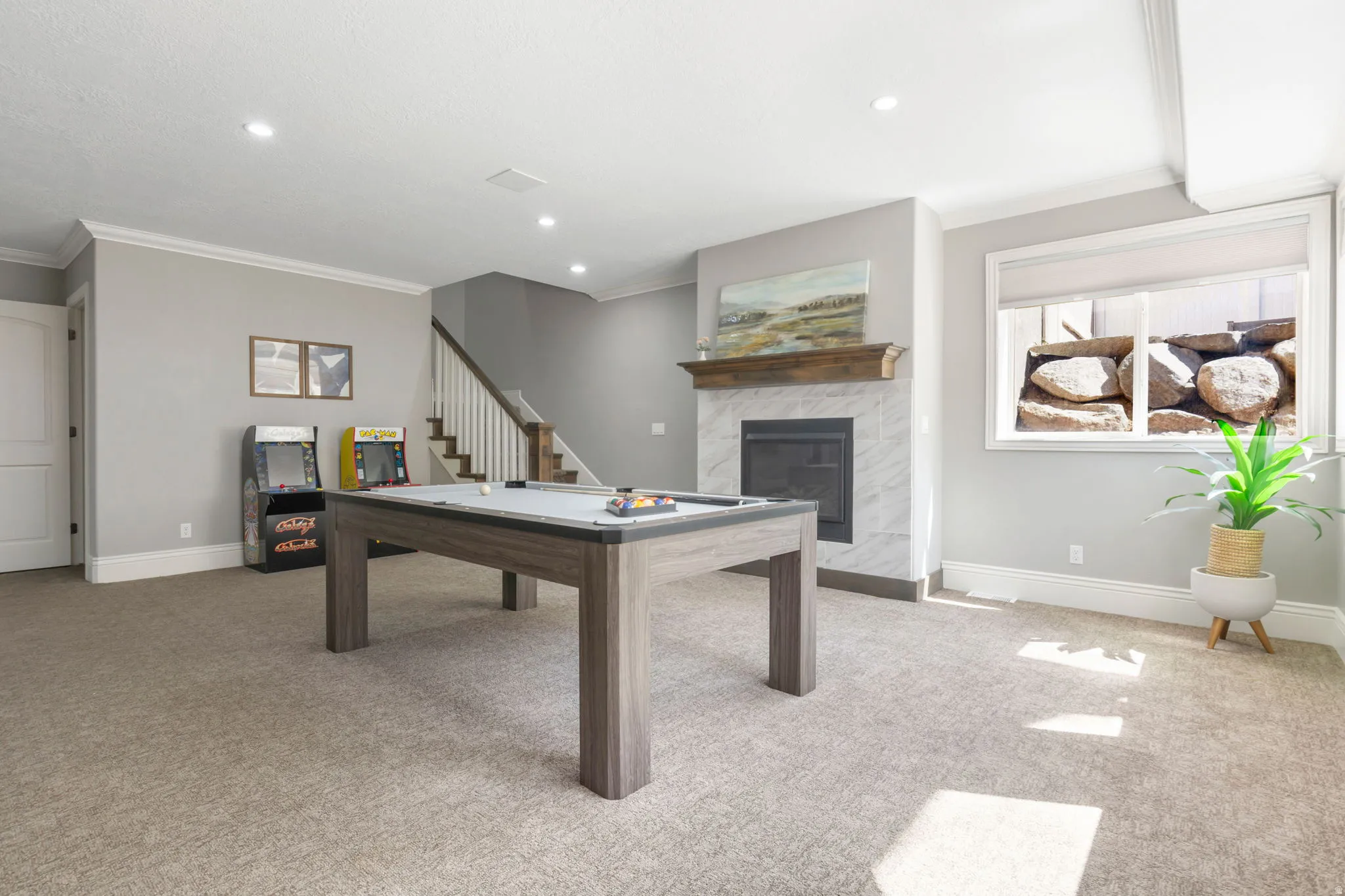 Recessed lighting, crown molding, fireplace with stone surround, wood mantel, and a staircase with white risers and wood treads