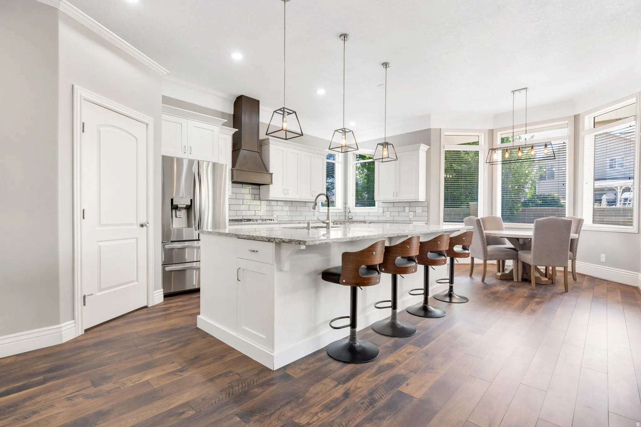 Kitchen featuring white cabinetry, a large center island with a light-colored countertop, stainless steel appliances, and wood-finish flooring