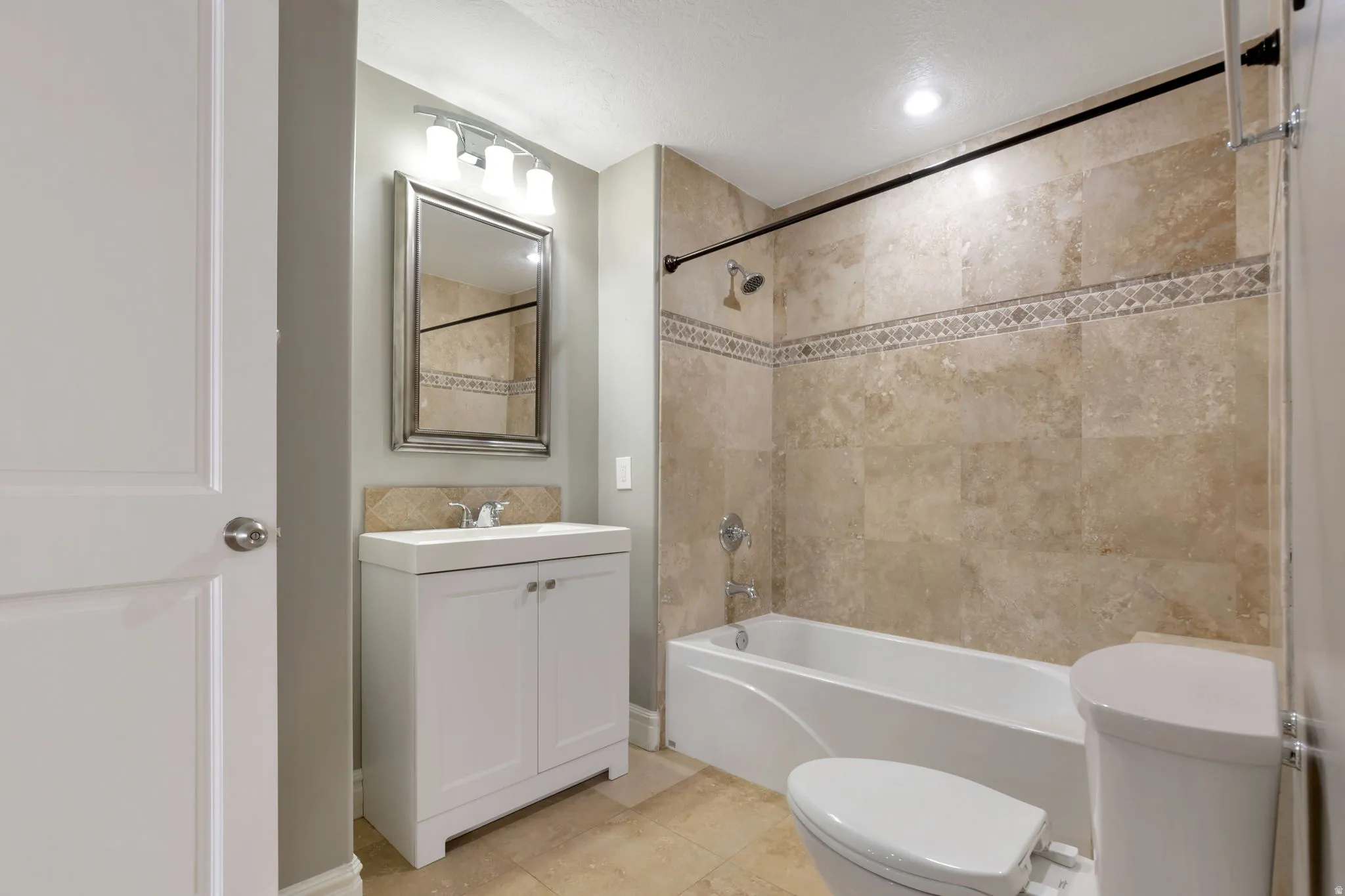 Bathroom featuring a white vanity with integrated sink, framed mirror, and three-light fixture