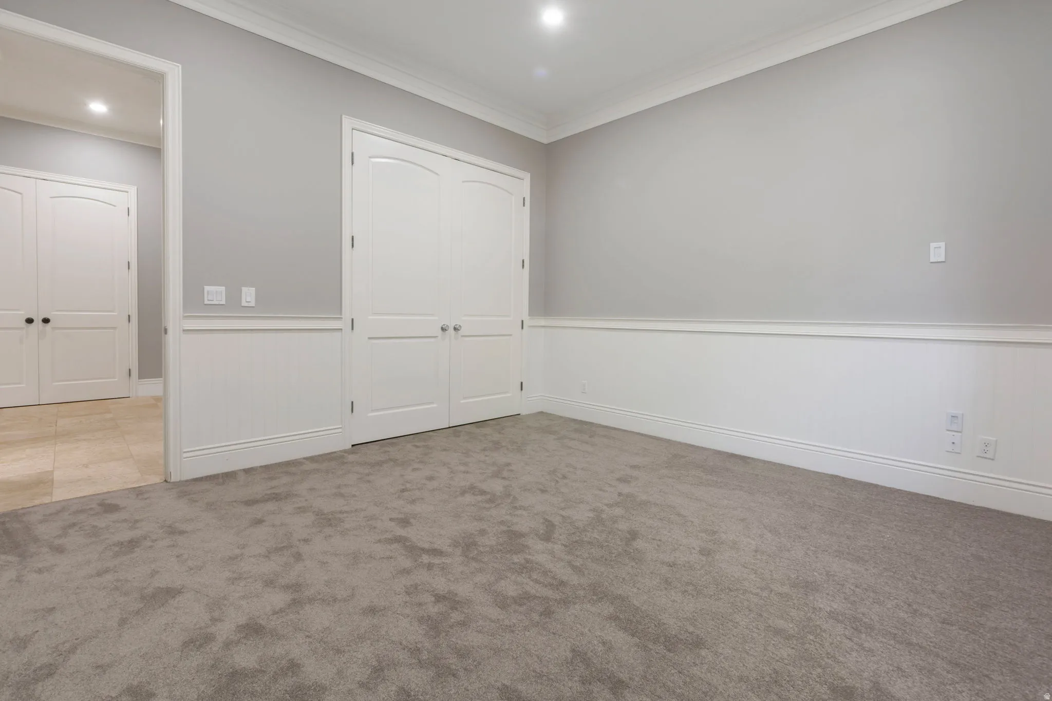 Plush gray carpeting, white wainscoting, recessed lighting, crown molding, and double-door entry