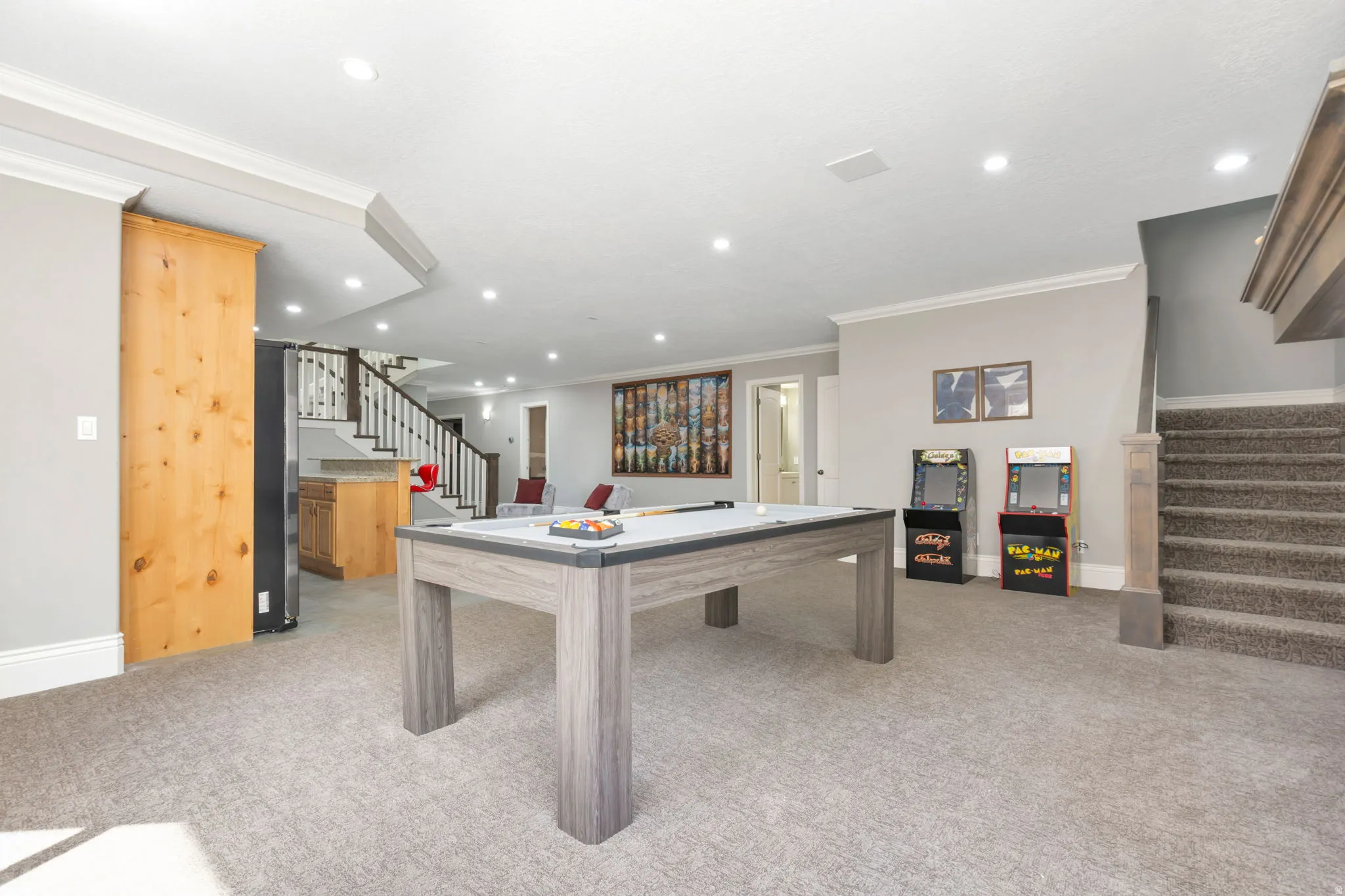 Recessed lighting illuminates the carpeted flooring and light grey walls