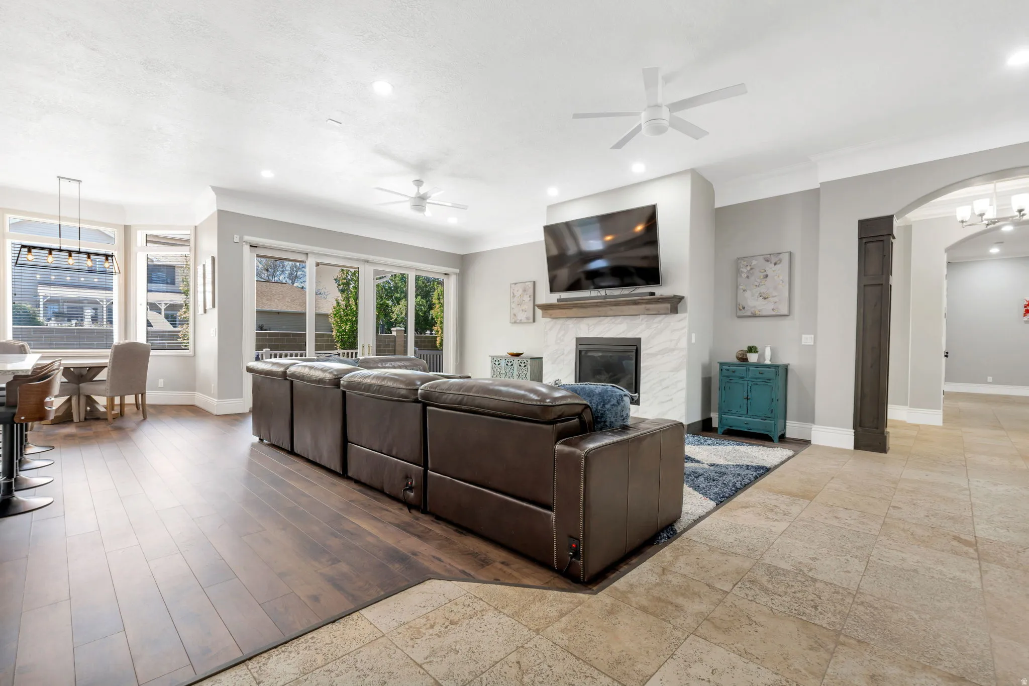 Spacious living area featuring wood-finish flooring, a fireplace with a stone surround, and glass sliding doors