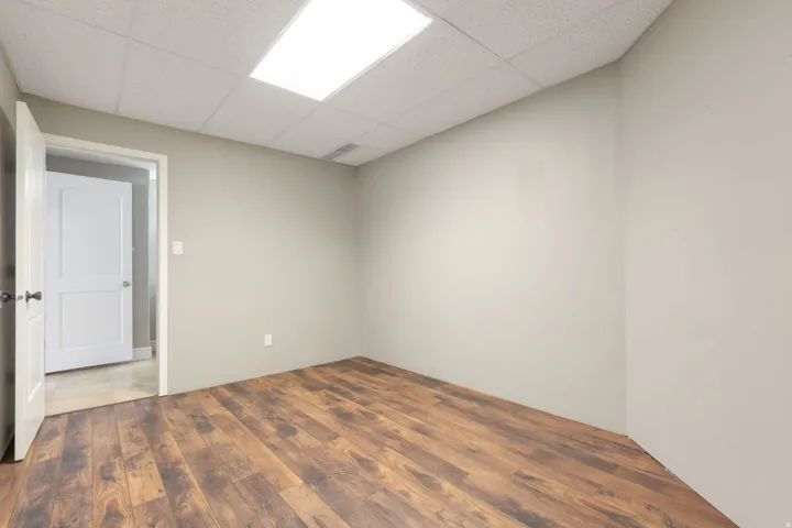 Wood-finish flooring, drop ceiling with integrated lighting, and neutral wall tones
