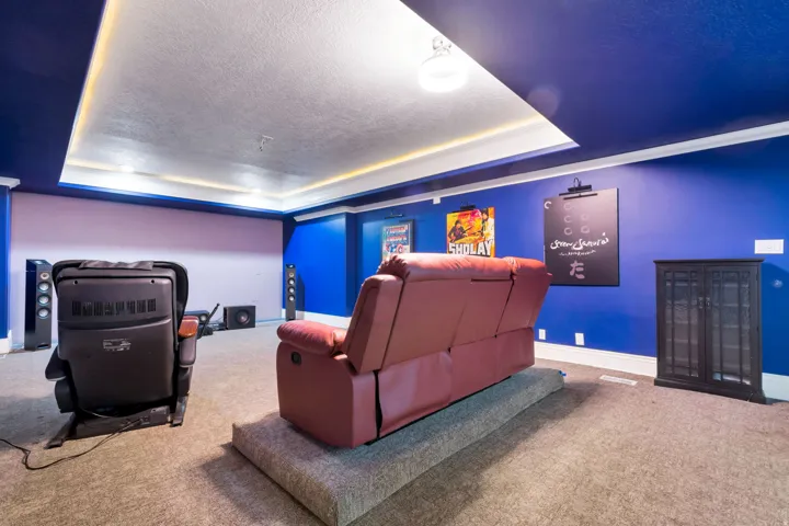 Recessed ceiling with perimeter lighting, wall-mounted light fixtures, built-in wall speakers, and carpet flooring