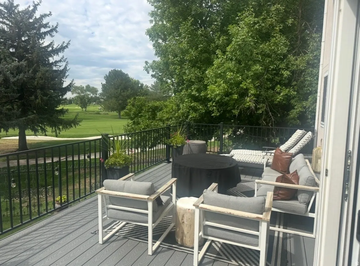 Spacious outdoor deck featuring composite decking, black metal railings, and a verdant golf course backdrop