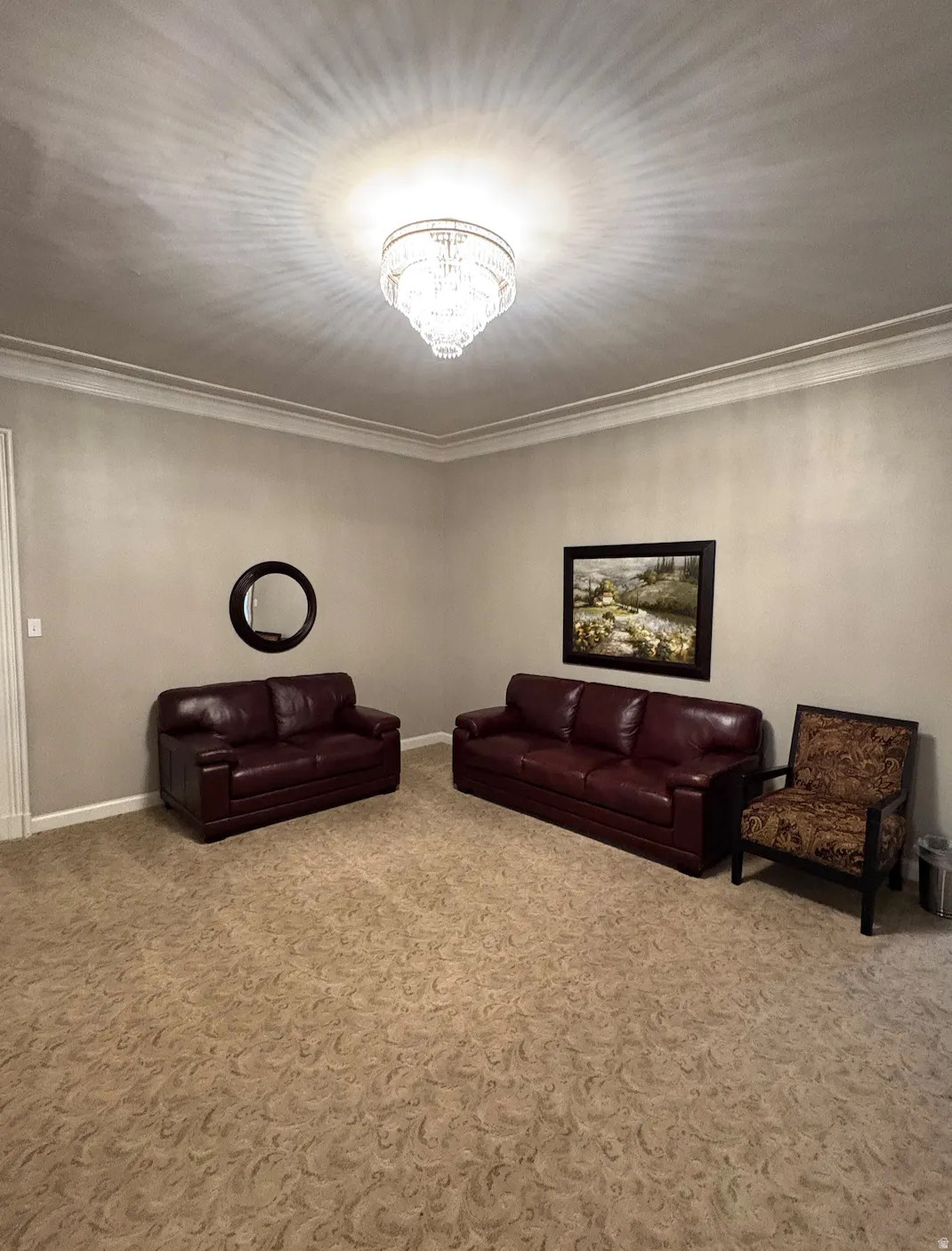 Recessed lighting, crown molding, patterned carpeting, neutral wall tones, and an ornate ceiling fixture