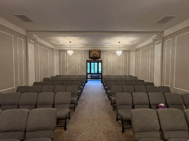 Decorative wall paneling, dual crystal chandeliers, recessed ceiling speakers, patterned carpeting, and a built-in pipe organ