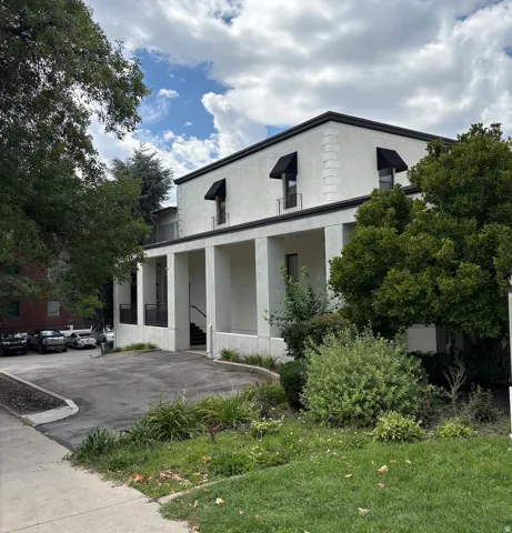 Stucco exterior with black awnings, black trim, and a paved parking area