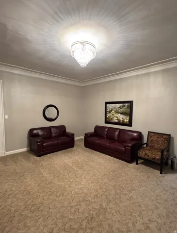 Recessed lighting, crown molding, patterned carpeting, neutral wall tones, and an ornate ceiling fixture