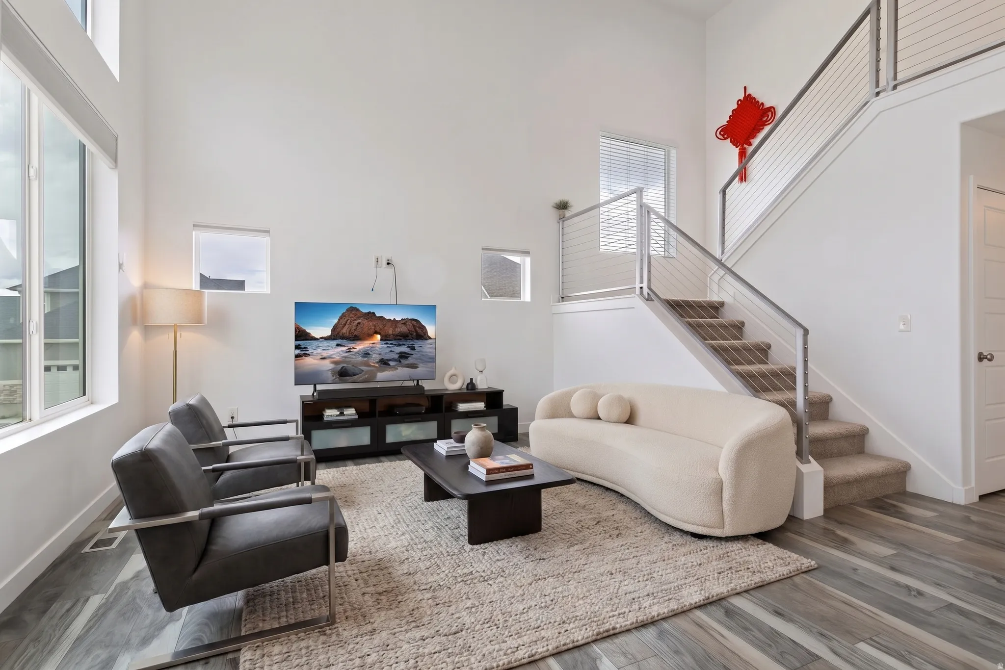 VIRTUALLY STAGED | High ceilings, large windows, wood-finish flooring, and a staircase with cable railing