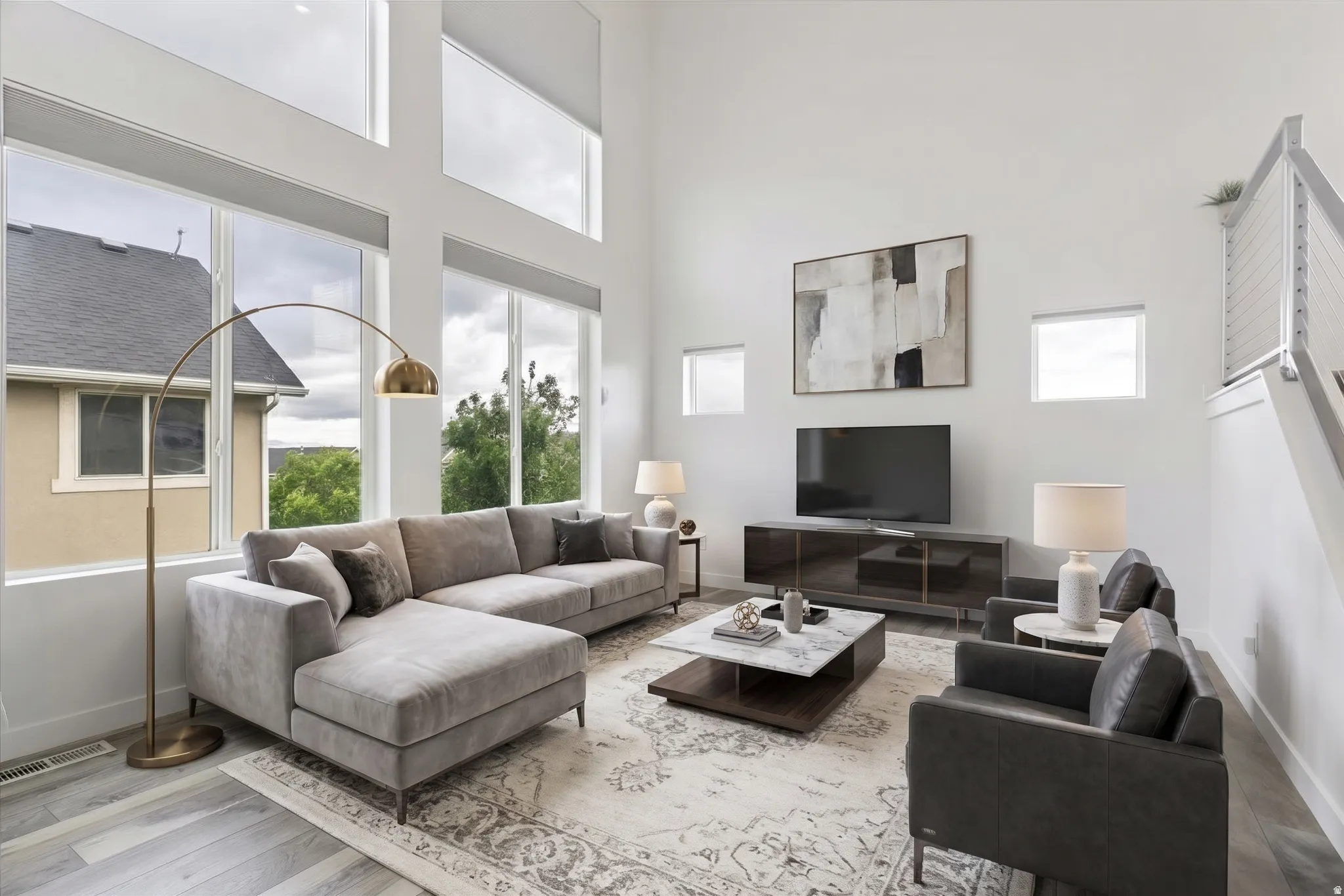 VIRTUALLY STAGED | Two-story ceiling, abundant natural light, wood-finish flooring, white walls, and a contemporary cable railing system