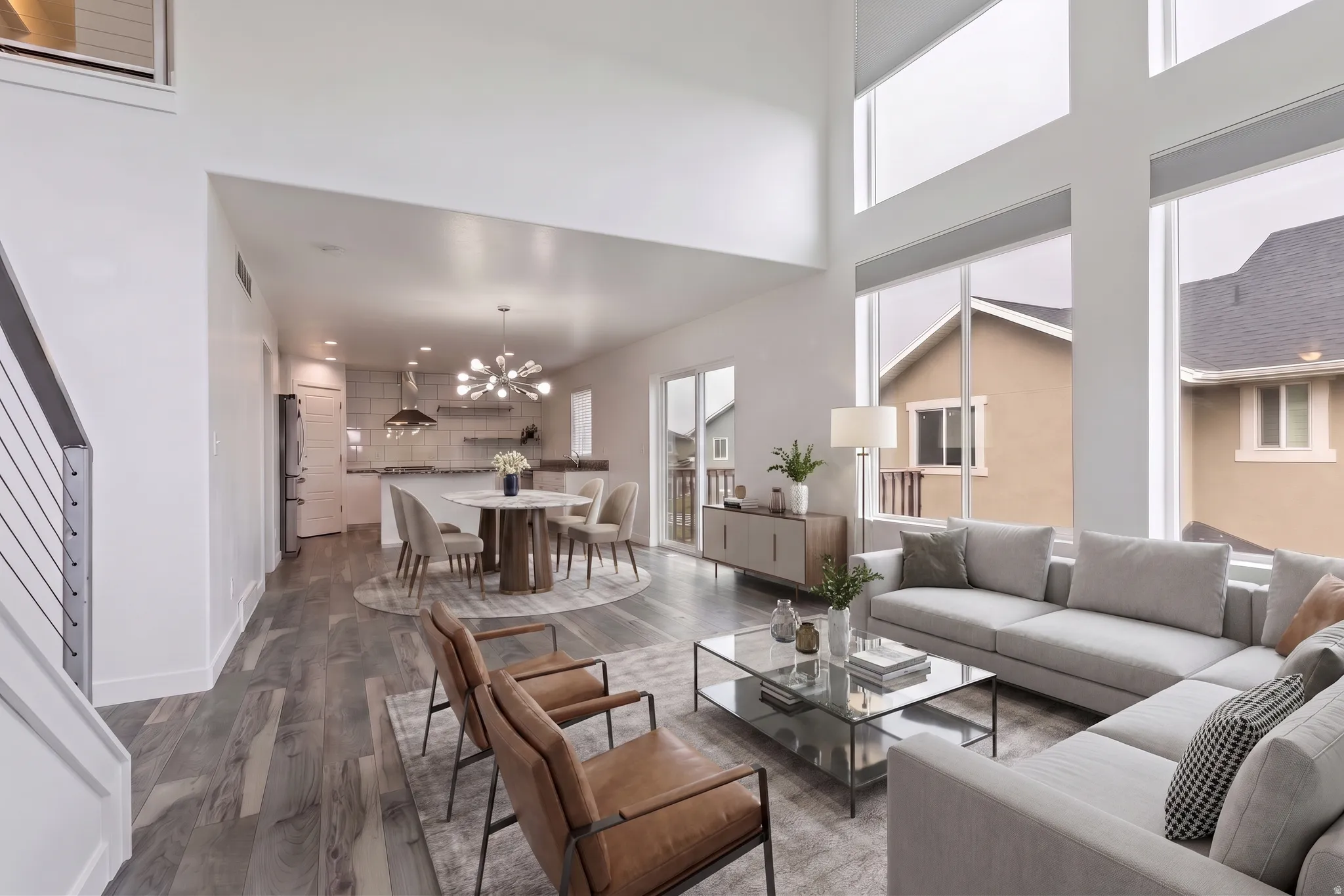 VIRTUALLY STAGED | Vaulted ceilings with expansive windows, wood-finish flooring, kitchen island with seating, built-in shelving, and contemporary light fixtures