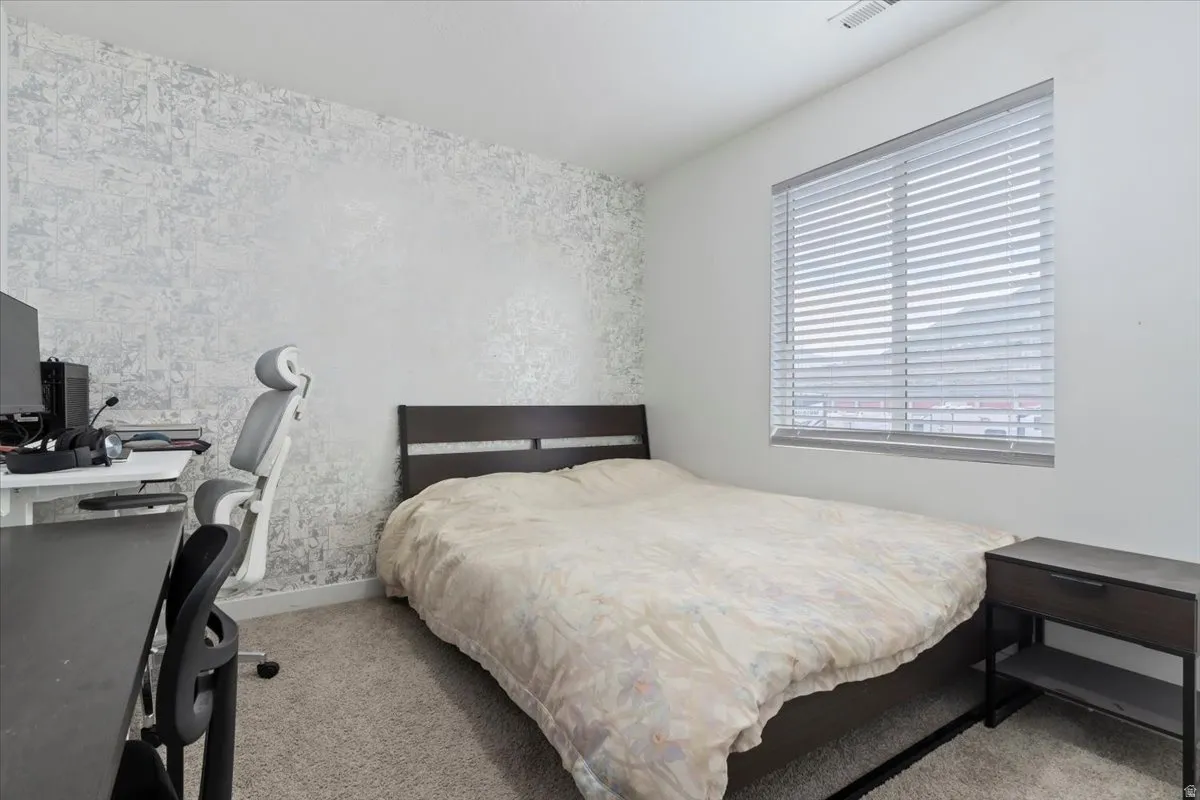 Textured accent wall, window with horizontal blinds, neutral carpeting