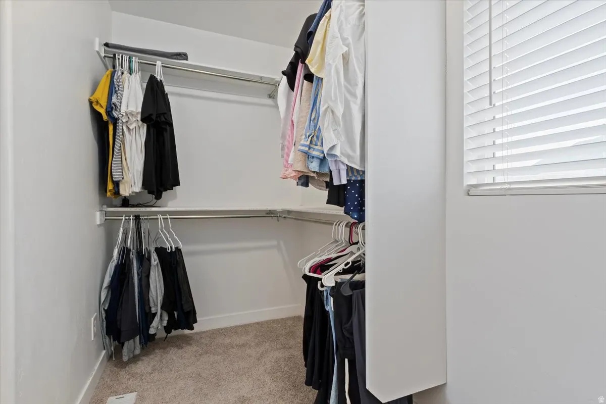 Built-in closet shelving system with multiple hanging rods and a window with blinds