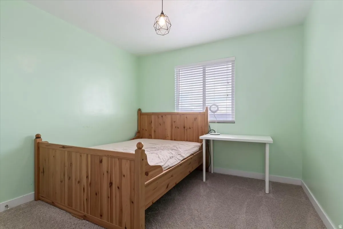 Window with horizontal blinds, overhead geometric pendant light fixture, and light green walls