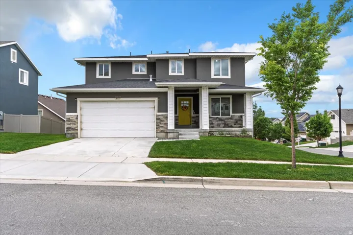 Contemporary exterior with a two-car garage, concrete driveway, and covered front porch with stone accents
