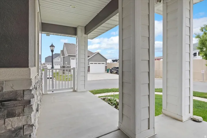 Covered porch featuring a concrete surface, white shingle-style columns, and a stacked stone wall accent