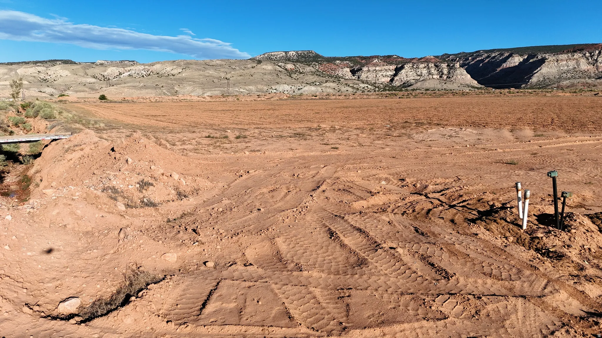 Expansive open land with visible utility connections and distant mountain ranges