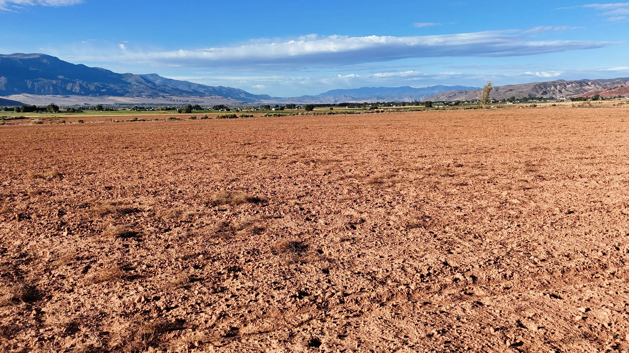 Expansive open land with a distinct red-brown soil and distant mountain range