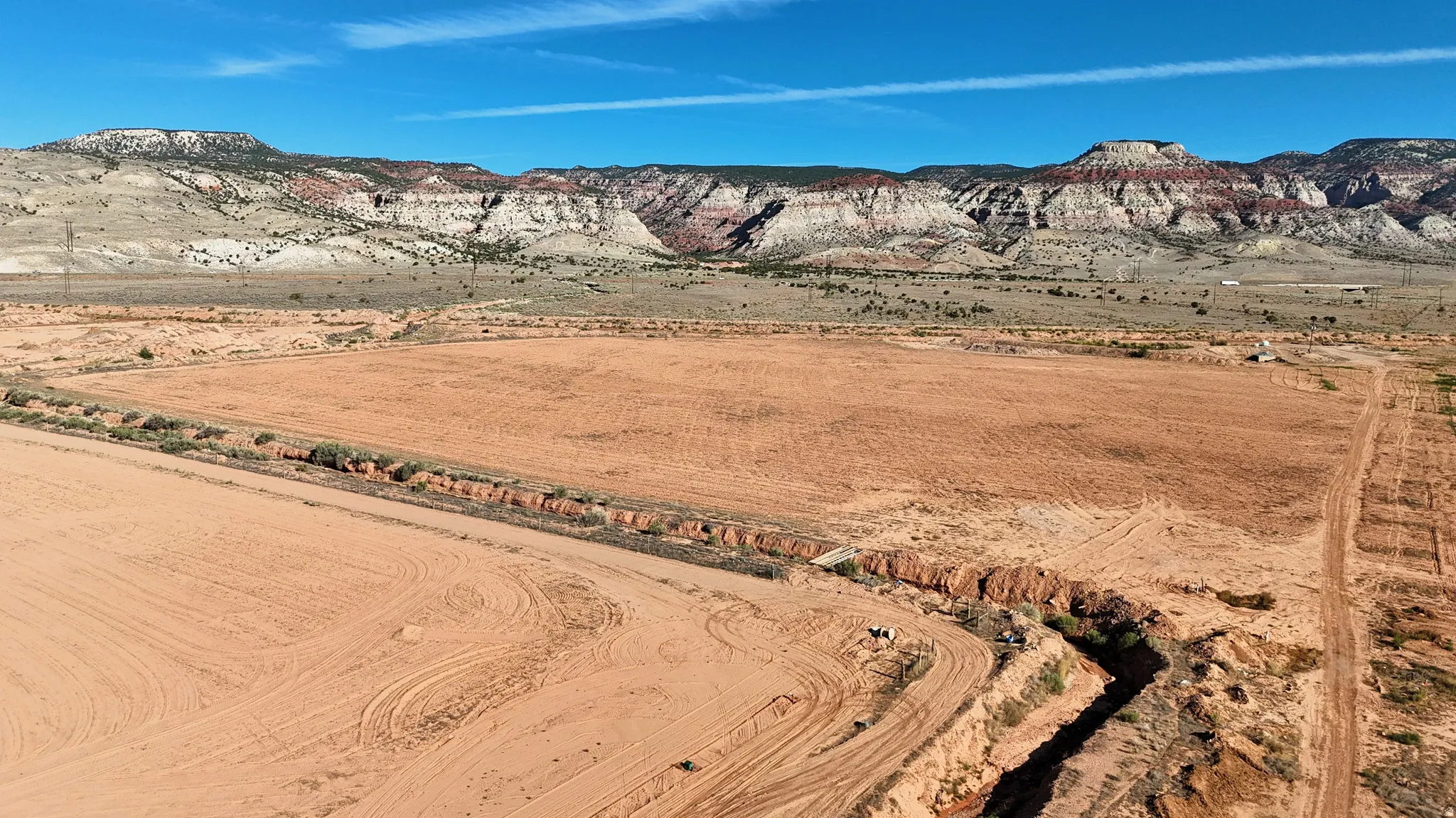 Expansive land parcel with clear ground, bordered by natural terrain and distant mountains