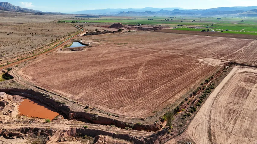 Expansive open land with tilled soil, two visible ponds, and a distinct dirt road