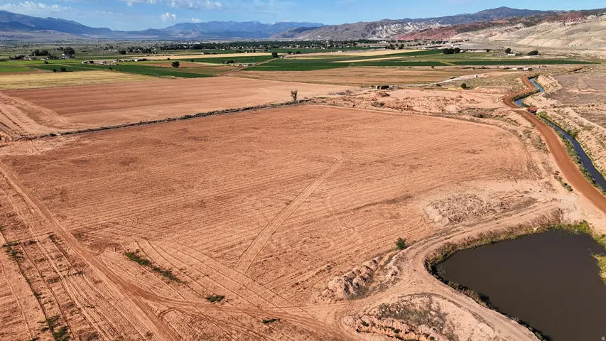 Expansive land parcel featuring a water channel, a natural pond, and cultivated fields