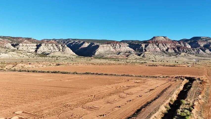 Expansive open terrain with visible land preparation, bordered by natural rock formations
