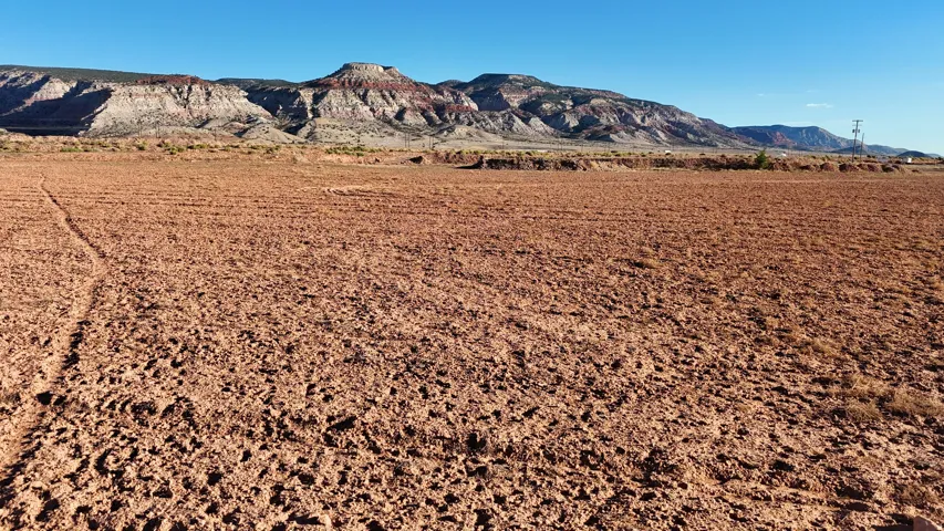 Expansive land featuring a tilled earth surface and distant mountain ranges
