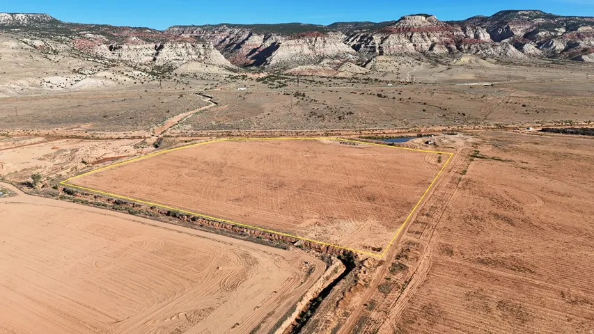 Expansive open land with a defined perimeter, featuring a distant mountain backdrop and a visible body of water