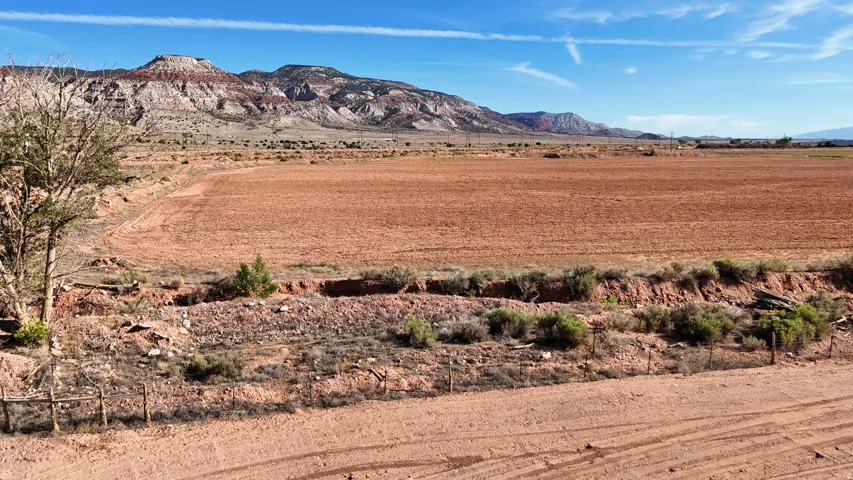 Expansive cleared land with distant mountains under a blue sky