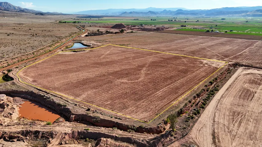 Expansive cultivated land featuring a defined perimeter, natural water features, and distant mountain ranges