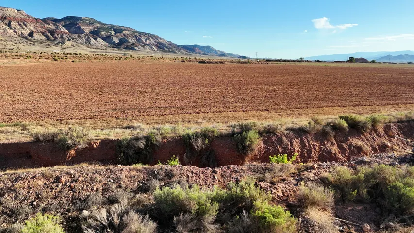 Expansive cleared land parcel with natural vegetation, featuring a prominent mountain backdrop